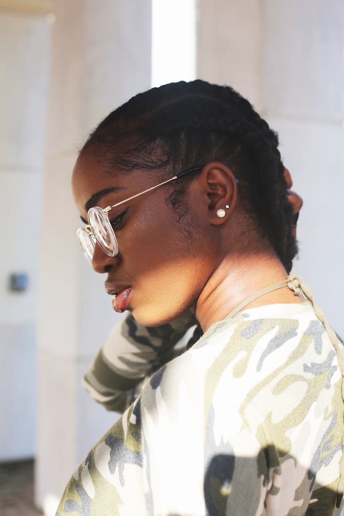 Side profile of a fashionable woman in camouflage clothing, wearing glasses and earrings.