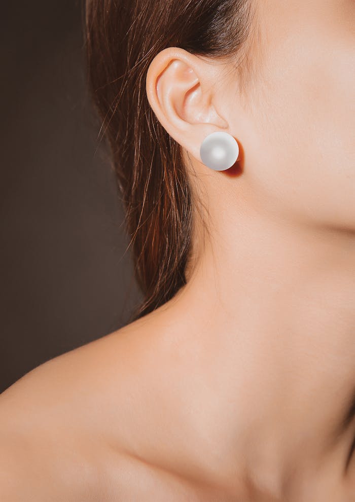 A close-up of an elegant pearl earring on a woman's ear, displaying grace and style.